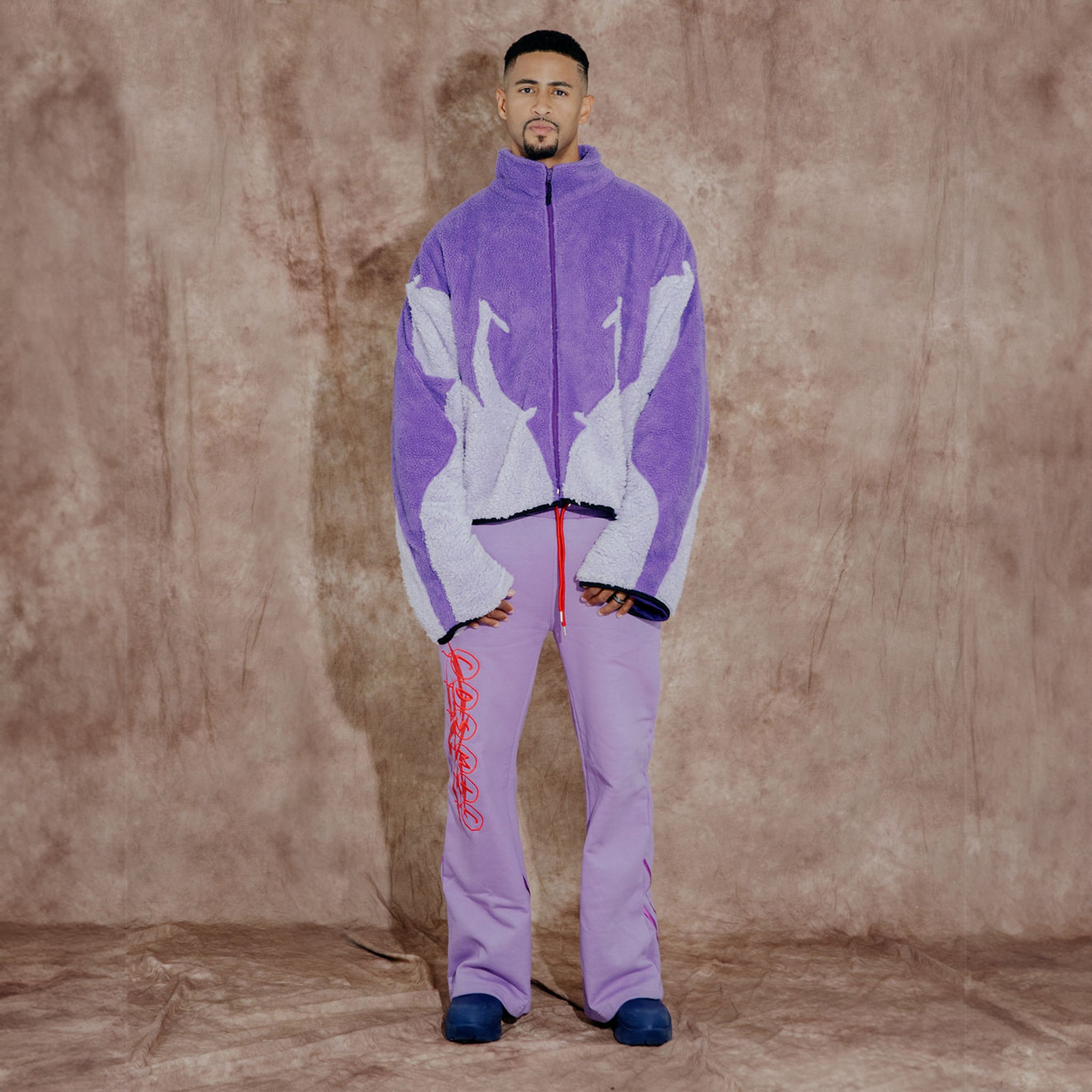 Cosmic the Oasis three-color purple sherpa zip up with extended sleeves can be worn as an oversized shirt layer or outerwear. Dramatic curved design with Cosmic logo across the back.