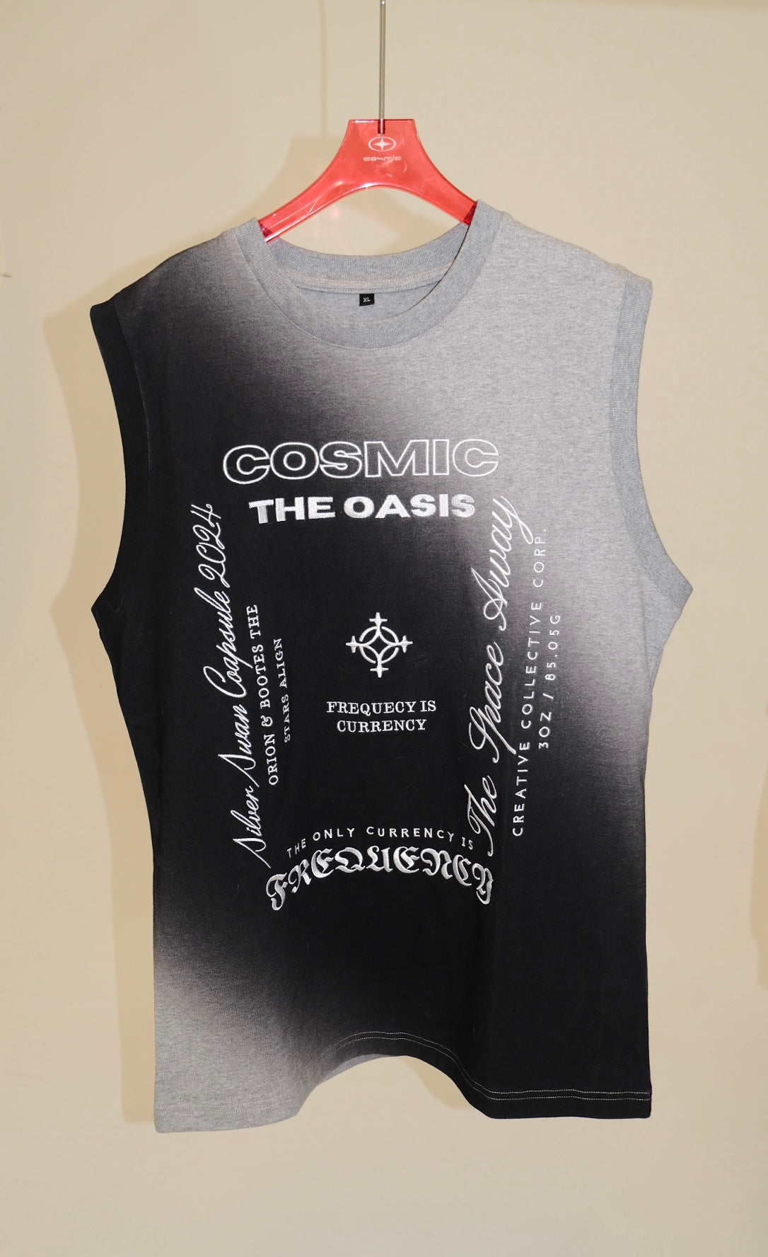 Black and gray tank top with text on a hanger against a beige wall
